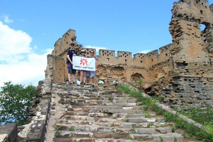 A historical stone staircase leading up to a large brick wall with a banner held by two people. 3