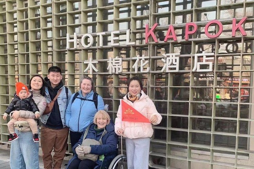 Un gruppo di persone davanti a un edificio con un cartello che recita 'HOTEL KAPOK'. 3