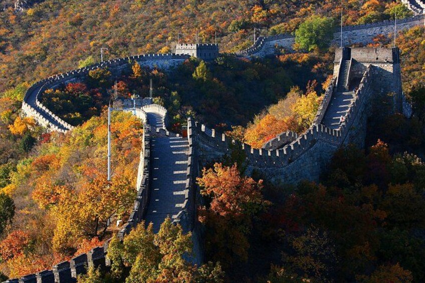 The Great Wall of China winding through a mountainous landscape with autumn foliage. 1