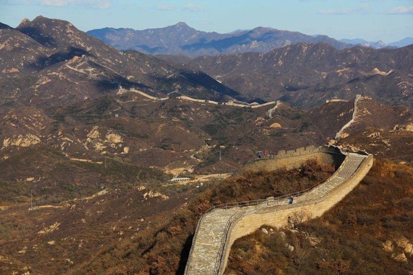 A mountainous landscape with a winding road and a stone wall. 5