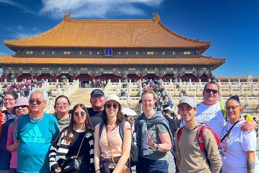 Eine Gruppe von Menschen vor einem traditionellen chinesischen Gebäude mit goldenem Dach und roten Wänden. 4