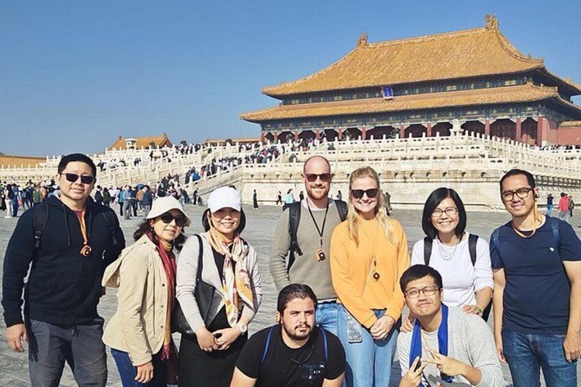 A group of people standing in front of a large, traditional building with a golden roof and white walls. 3