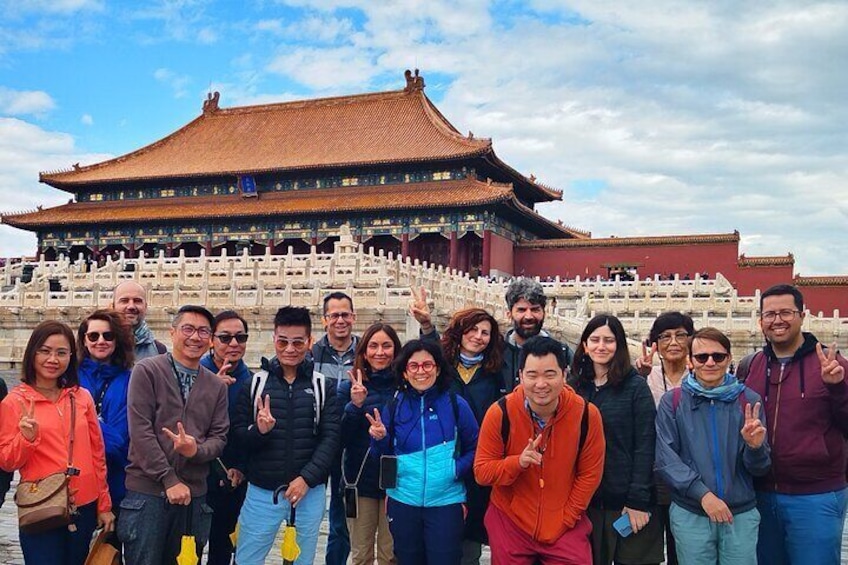 A group of people standing in front of a traditional Chinese building with a red roof and white walls. 1