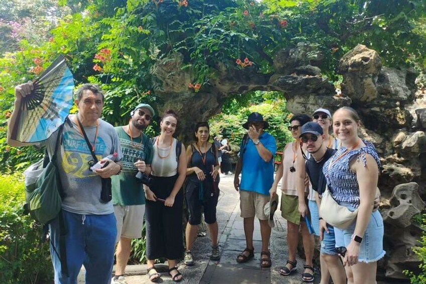Un grupo de personas de pie bajo un arco de piedra en un jardín. 3