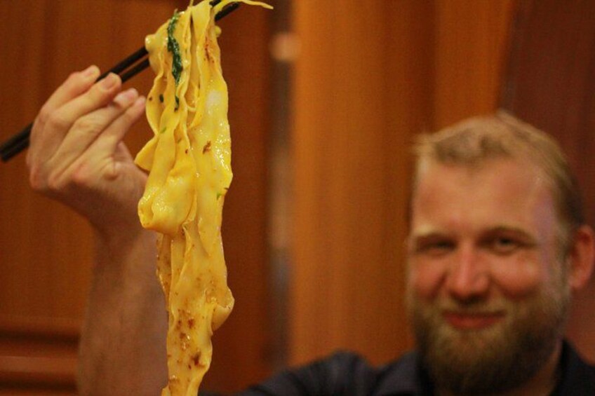A person holding a noodle with chopsticks. 3