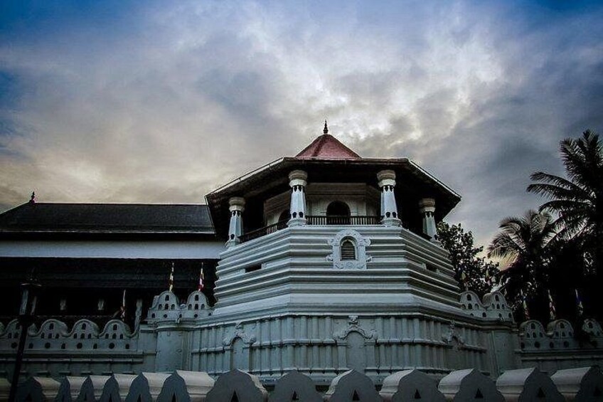 A historical building with a central dome and a red roof, surrounded by a white fence with decorative elements. 4
