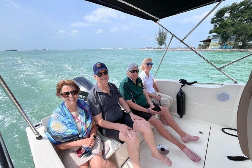 A boat with four people on board, water, and a distant shoreline. 4