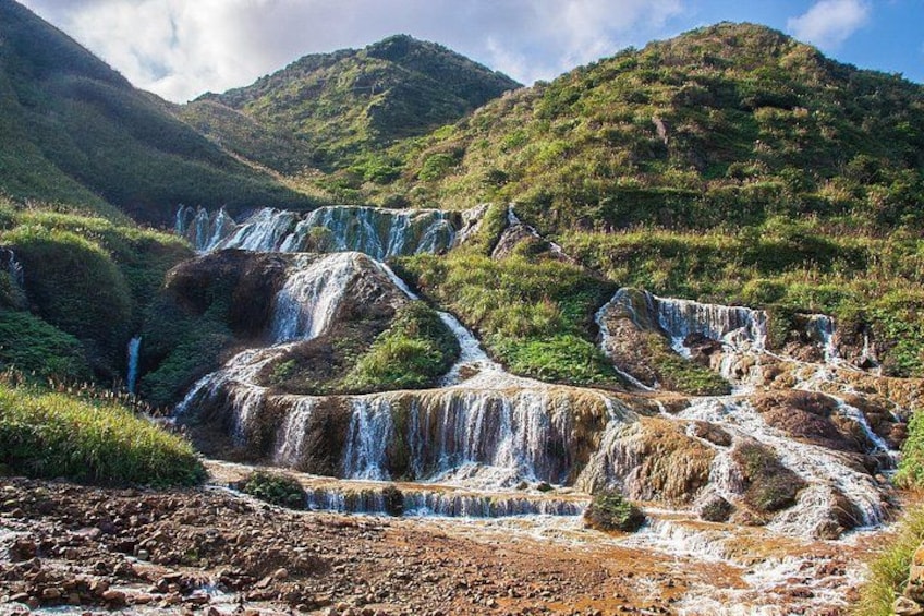 Una serie de cascadas en cascada rodeadas de colinas verdes y exuberantes. 4