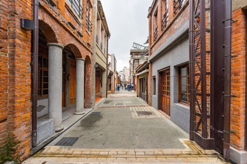 A narrow alley with brick buildings, columns, and a paved walkway. 3