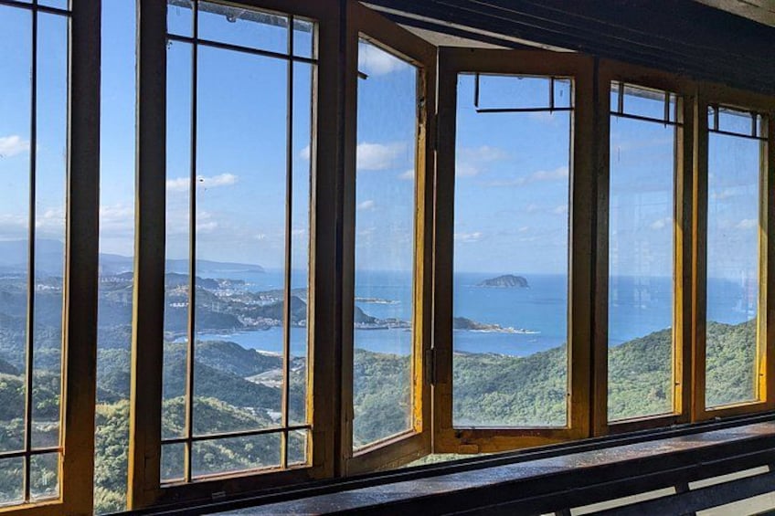 Fantastisk panoramaudsigt gennem store vinduer ud over et kystlandskab med bakker og en fjerntliggende ø. 5