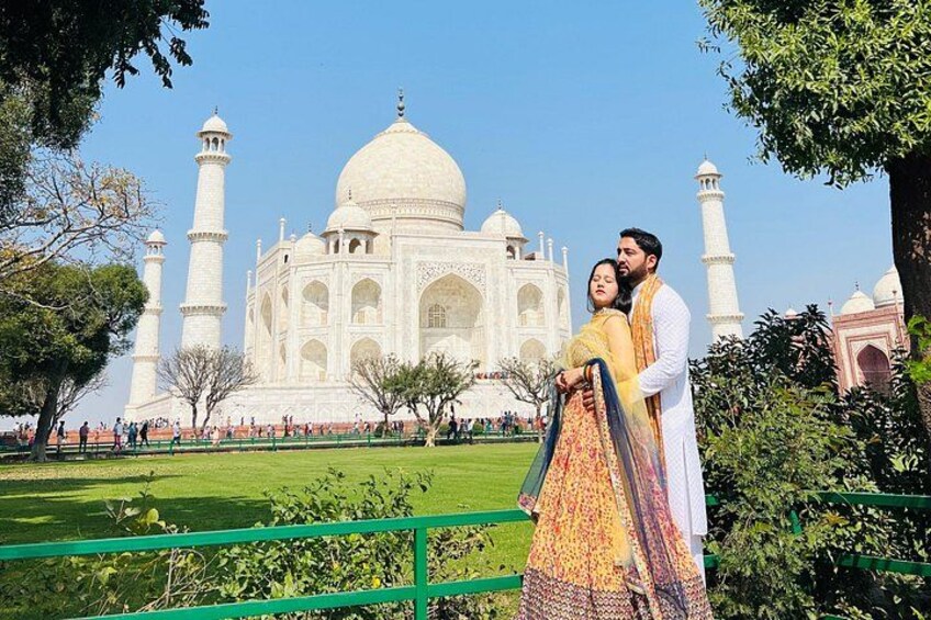 El Taj Mahal con una pareja vestida con atuendos tradicionales posando frente a él. 1