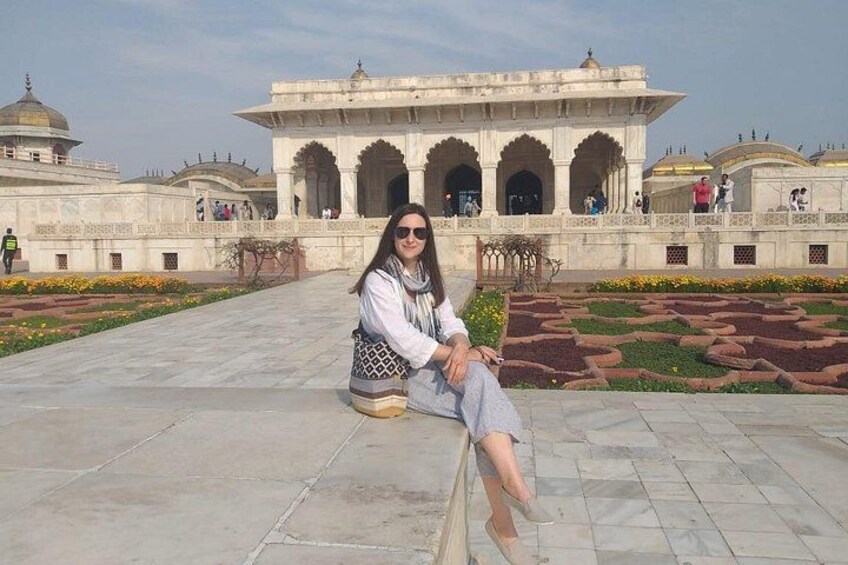 A person sitting on a bench in front of a large, ornate building with domes and arches. 2