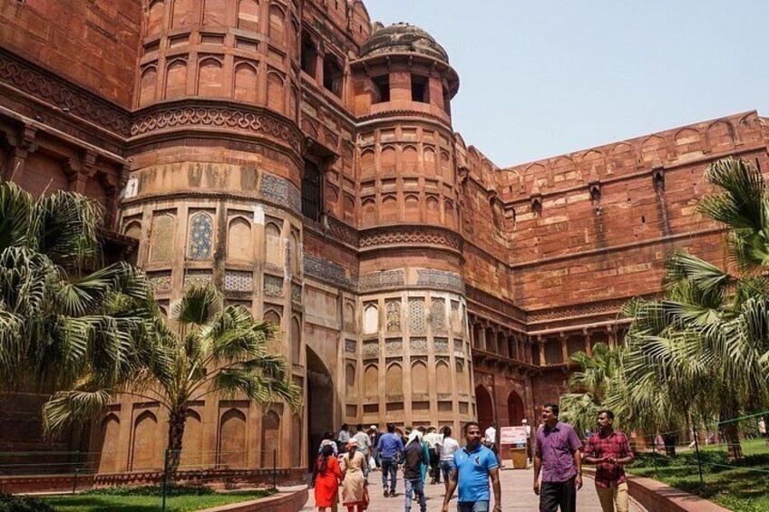 A historic building with intricate architecture, palm trees, and a group of people. 2