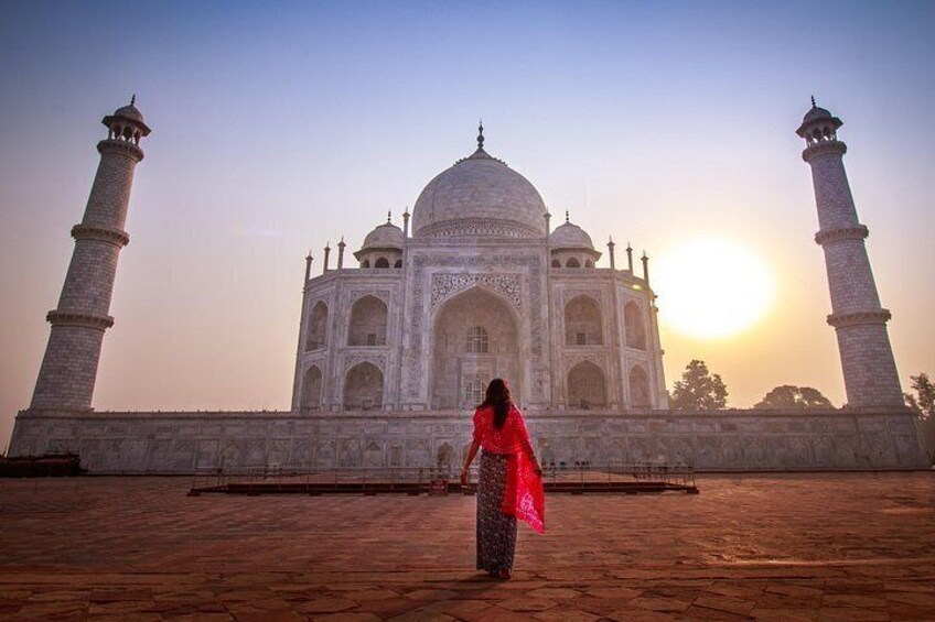 The Taj Mahal with a person in red attire standing in front of it. 4