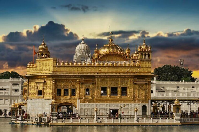 The Golden Temple with ornate architecture and domes, surrounded by a water body and people. 4