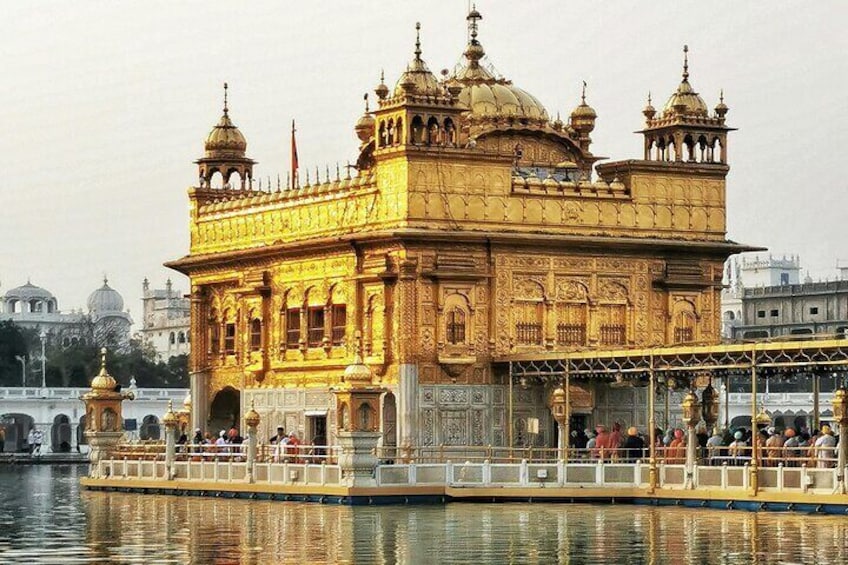 The Golden Temple with its golden facade and domes, surrounded by a water body and a bridge in the background. 2