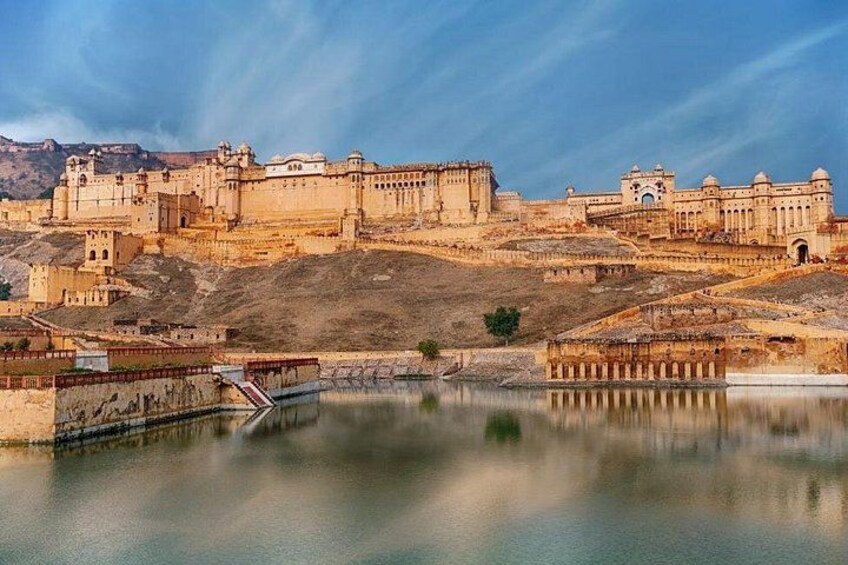 A historic fort with a river in the foreground, a bridge, and a hilltop structure. 2