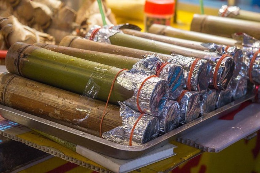Bamboo sticks wrapped in aluminum foil and tied with red bands, displayed on a metal rack. 4