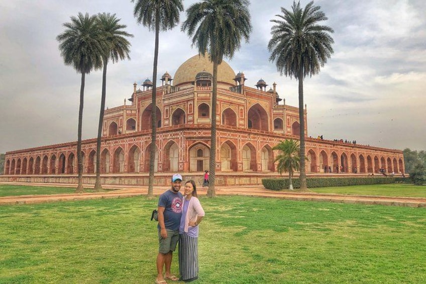 A large, historic building with a dome and arched windows, surrounded by palm trees and a grassy area. 3