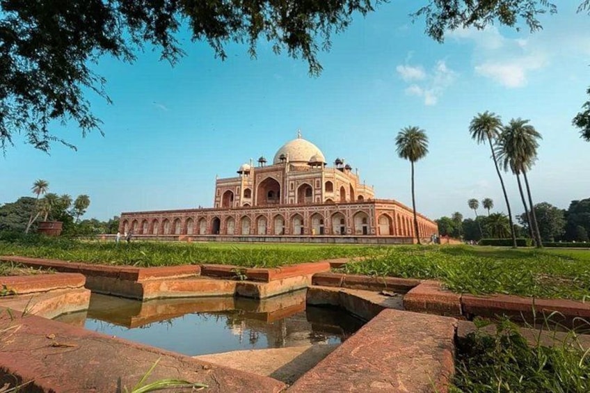 A large, historic building with a dome, surrounded by a water feature and palm trees. 1