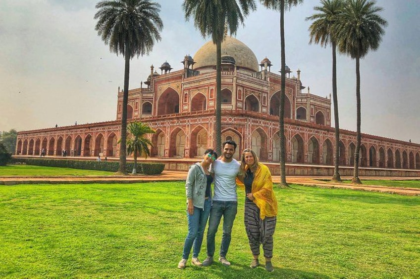 A large, historic building with domes and arches, surrounded by a well-maintained lawn and palm trees. 2