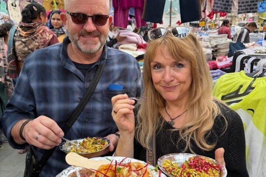 Two people at a market with food stalls. 3