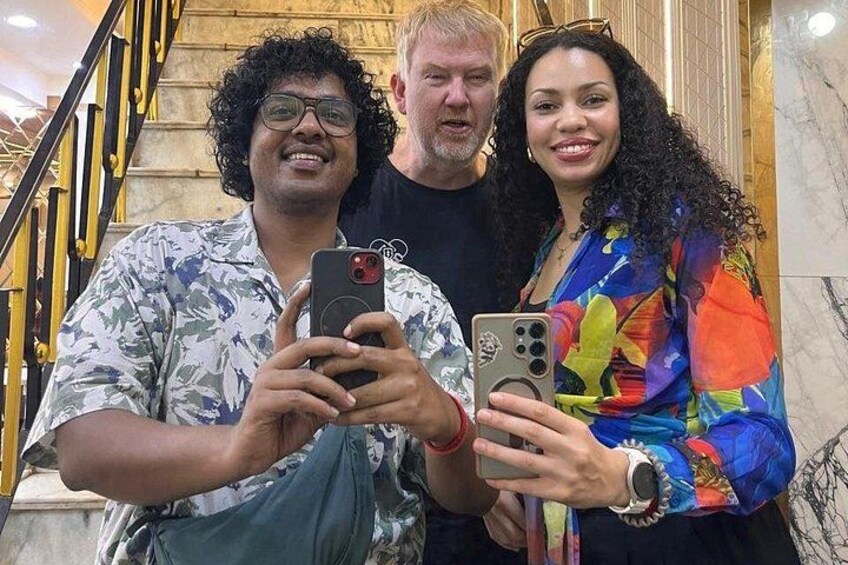 Three people taking a selfie in a marble-floored area with a staircase in the background. 2