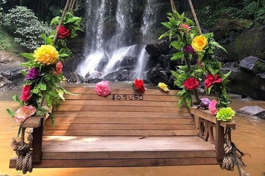 Een houten terras met kleurrijke bloemen en een waterval op de achtergrond. 4