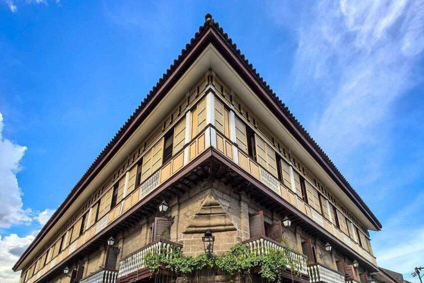 A historic building with a prominent corner, large windows, and a balcony with a fence. 2