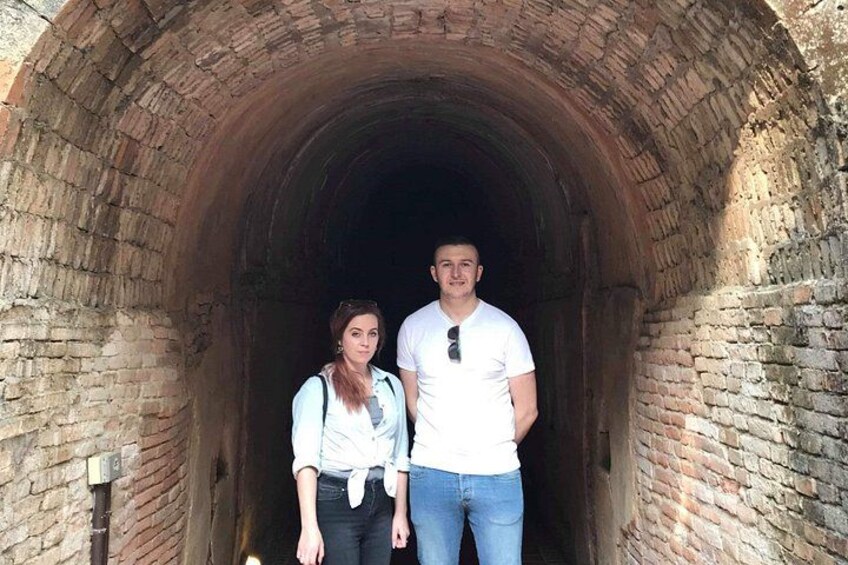 Dos personas de pie en un túnel de piedra con paredes de ladrillo. 2