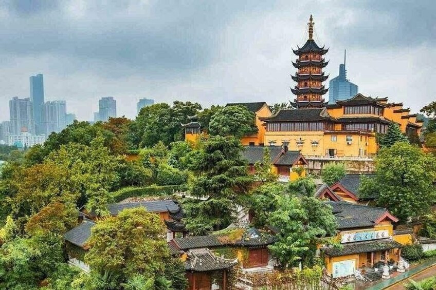 A traditional pagoda surrounded by lush greenery and modern buildings in the background. 5