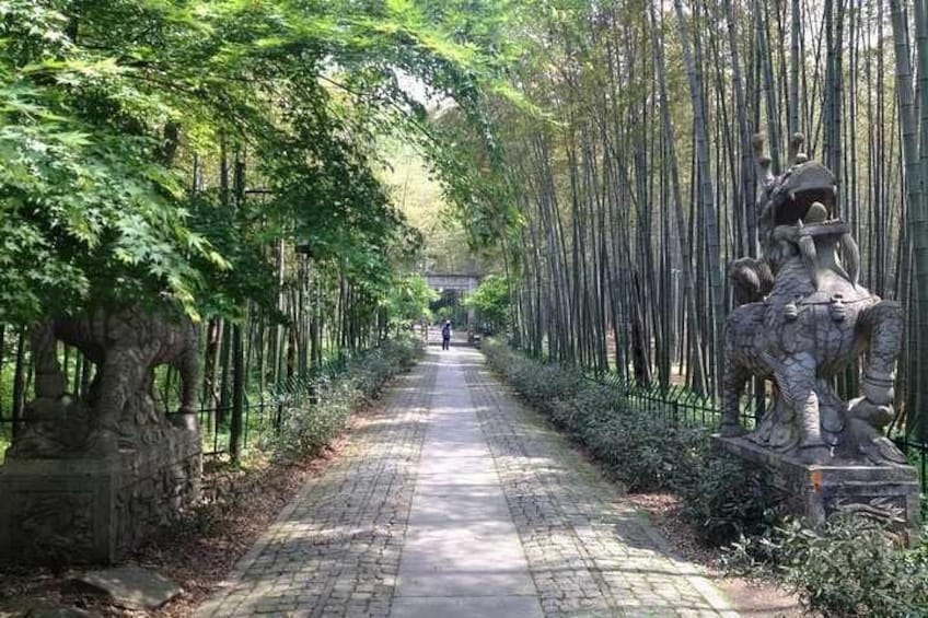 Un sendero bordeado de bambú y estatuas. 5