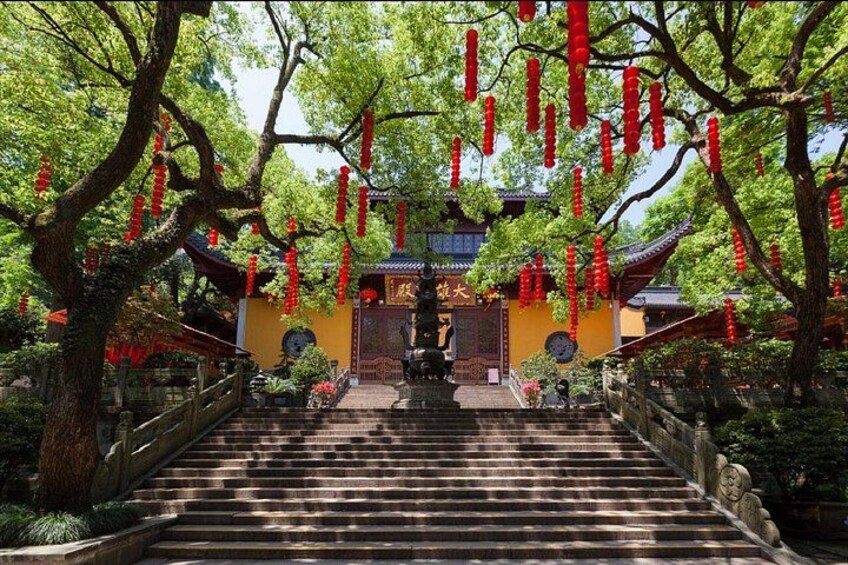 Una entrada de templo con escalones que conducen a un portón, rodeada de árboles y faroles rojos. 3
