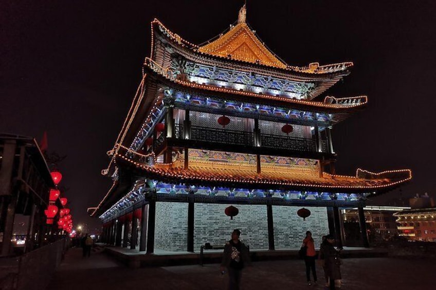 A traditional multi-tiered pagoda illuminated at night with people walking around. 3
