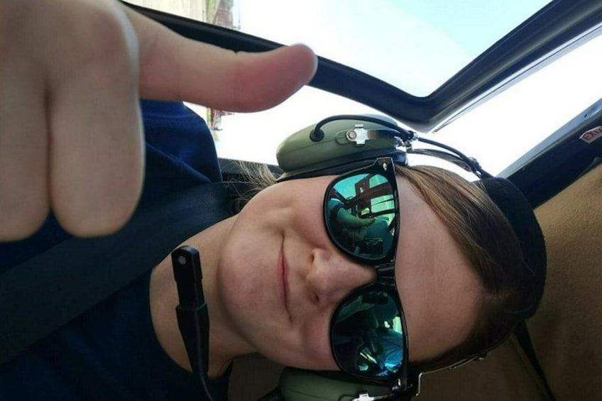 Eine Person mit Sonnenbrille und Kopfhörer sitzt in einem Fahrzeug. 3