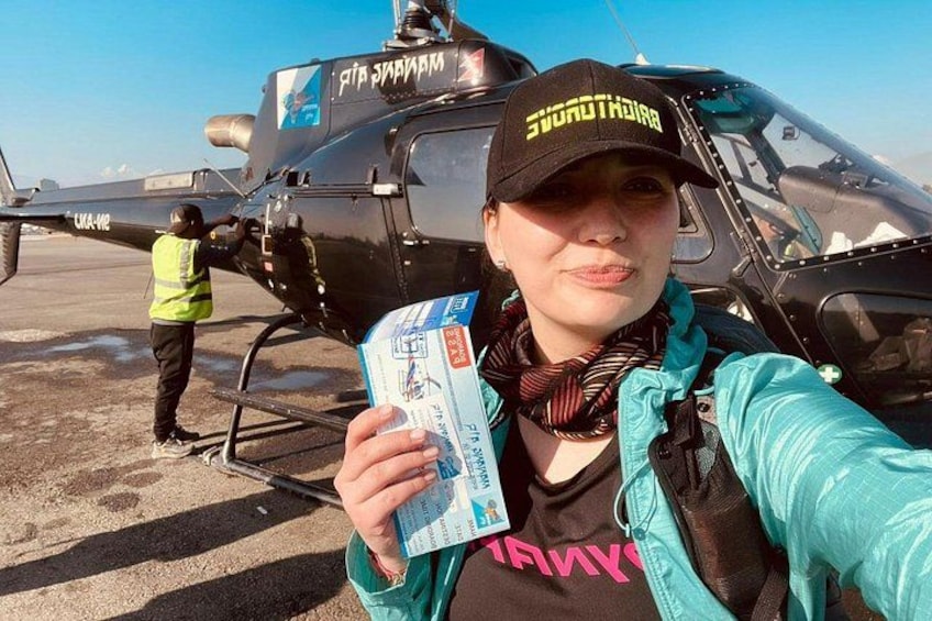 Eine Person hält ein Ticket vor einem Hubschrauber. 1