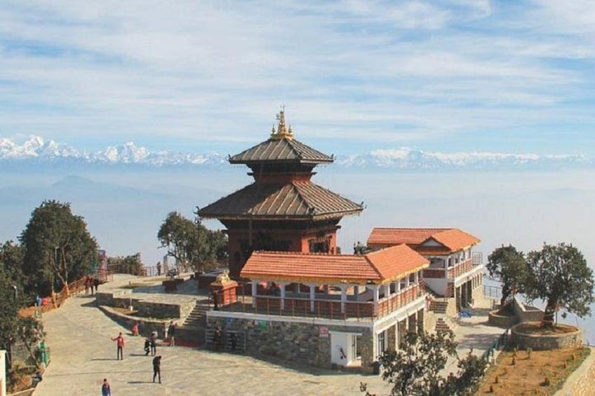 A traditional multi-tiered pagoda with a red roof, surrounded by a stone pathway and trees, with a mountain range in the background. 4