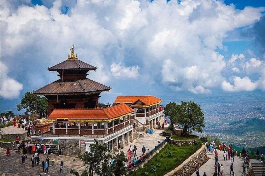 A traditional pagoda with a red roof, surrounded by a stone wall and a viewing platform with people. 5