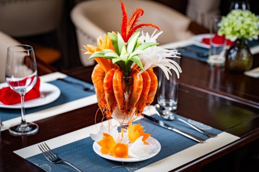 A table with a decorative centerpiece of shrimp, flowers, and greenery. 4