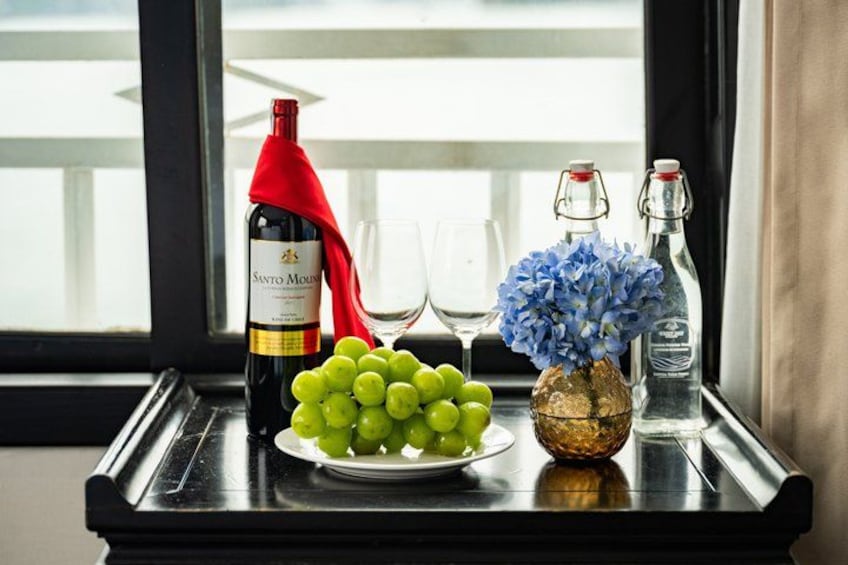 A bottle of wine, a plate of grapes, a glass, and a vase with flowers on a tray. 3