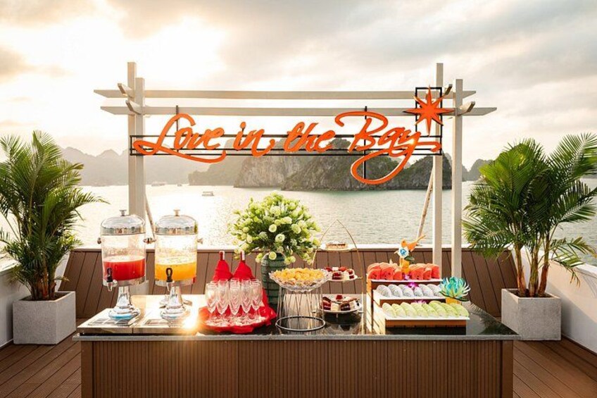 A buffet table with drinks, a cake, and a sign that reads 'Live in the Bay'. 3
