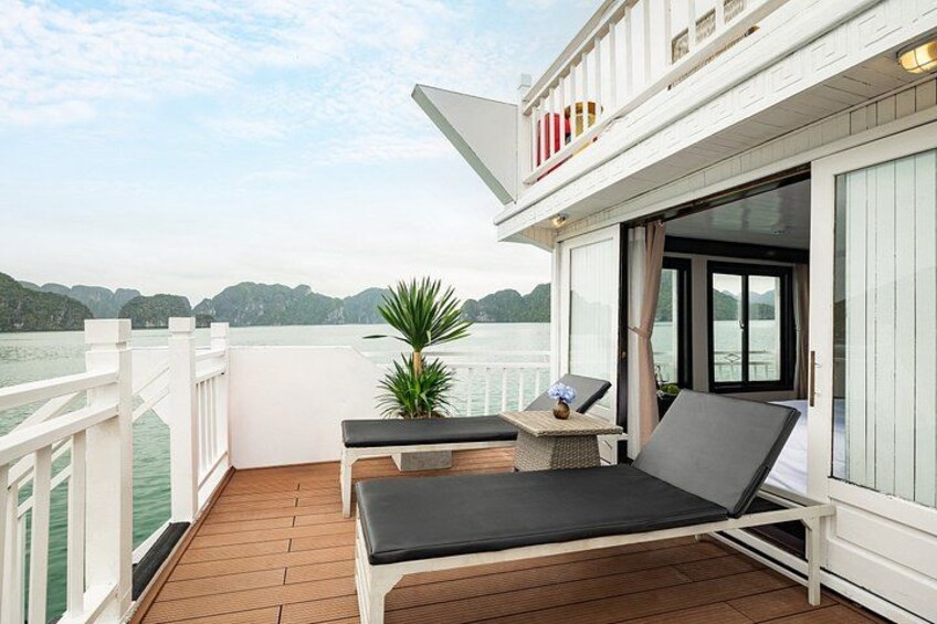 A wooden deck with a white railing, a table with a plant, and two lounge chairs. 5