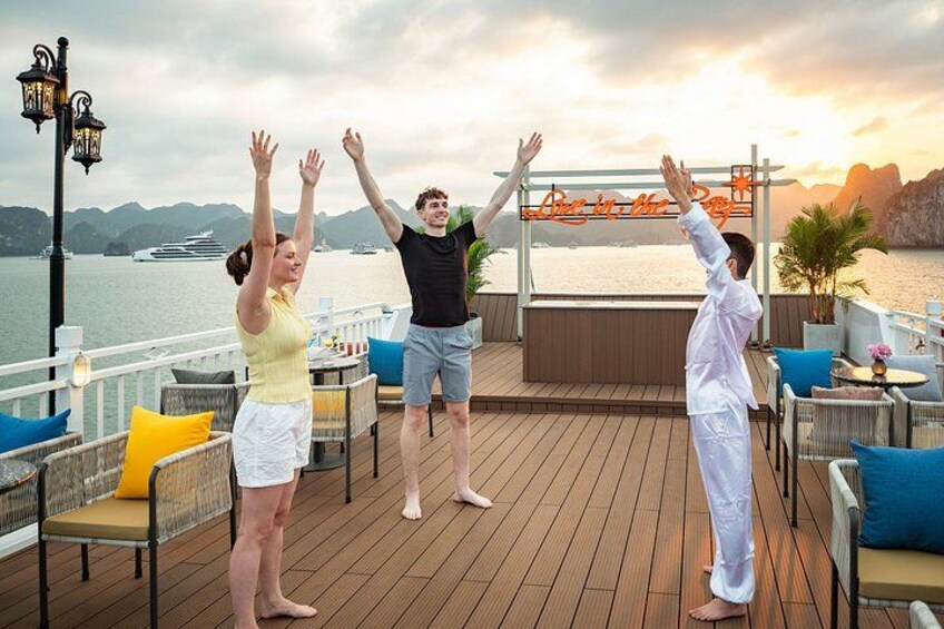 Three people performing a synchronized activity on a wooden deck with a view of a body of water and mountains in the background. 2