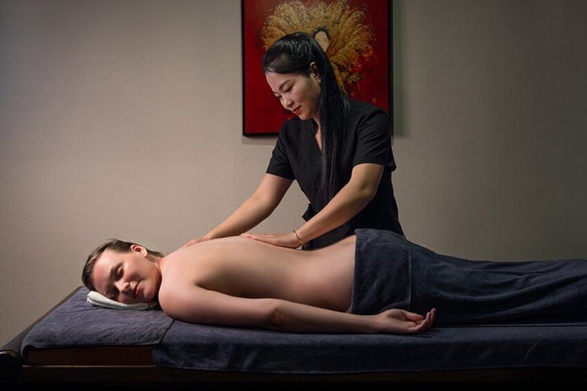A person receiving a massage on a massage table in a room with a red wall and a painting. 2