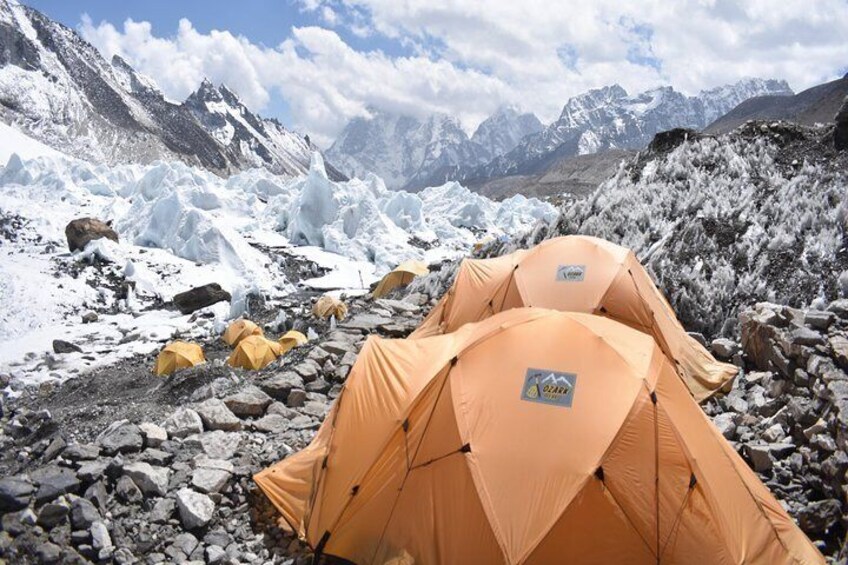 Två orange tält på ett bergigt, snötäckt berg med glaciärer i bakgrunden. 1