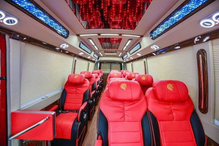 A train interior with red seats, a digital display, and red ambient lighting. 4