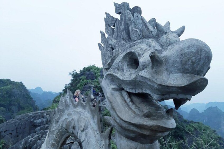 A large stone dragon sculpture with tourists climbing it. 2