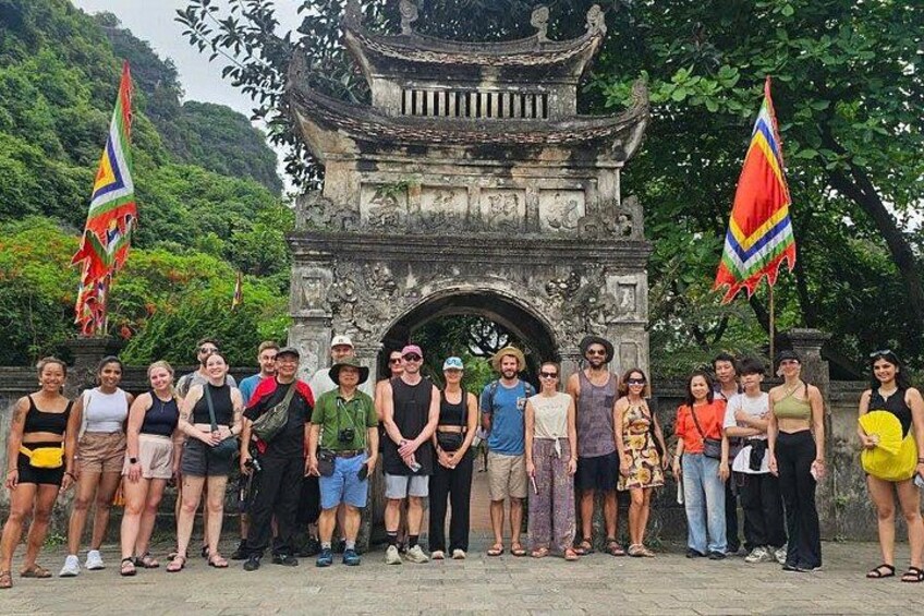 Un grupo de personas frente a un arco de piedra histórico con banderas. 4