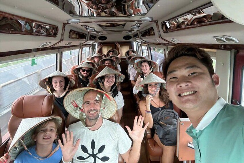 A group of people on a bus wearing traditional conical hats, seated in a row. 3