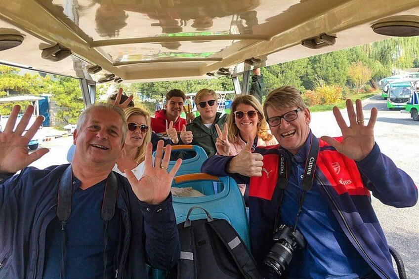 Un groupe de personnes à l’intérieur d’un véhicule, avec des bagages, qui agitent les bras et sourient. 4